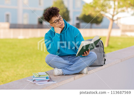 Student with book contemplates on campus 113687569