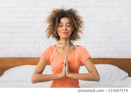 African-american woman sitting in namaste yoga position and relaxing 113687574