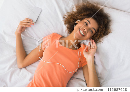 Young woman resting in bed with smartphone 113687628