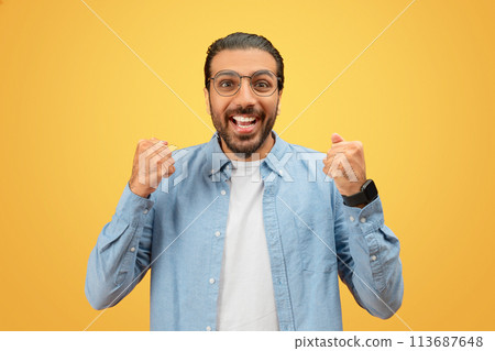 Excited man in glasses with clenched fists Excited man in glasses with clenched fists 113687648