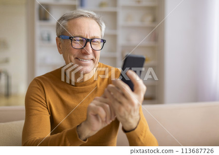 Smiling senior with glasses looking at phone Smiling senior with glasses looking at phone 113687726