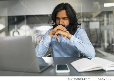 Focused man contemplating while working on laptop Focused man contemplating while working on laptop 113687829