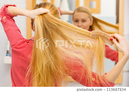 Woman combing her long hair in bathroom Woman combing her long hair in bathroom 113687834