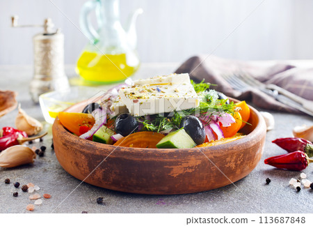 Greek salad of fresh cucumber, tomato, sweet pepper, lettuce, red onion, feta cheese and olives with olive oil. Healthy food, top view Greek salad of fresh cucumber, tomato, sweet pepper, lettuce, red onion, feta cheese and olives with olive oil. Healthy food, top view 113687848