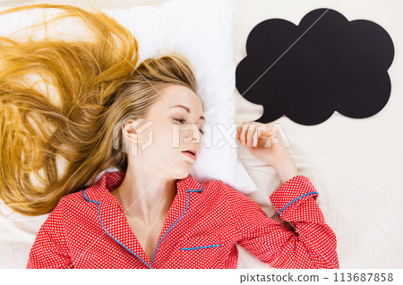 Young woman lying on bed wearing pajamas Young woman lying on bed wearing pajamas 113687858