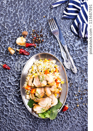 The concept of oriental cuisine. National Uzbek pilaf with meat in a cast-iron skillet, on a stone table. 113687891
