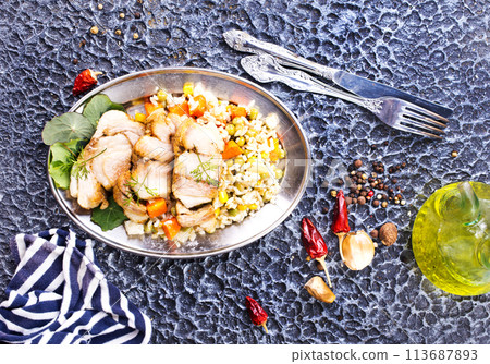 The concept of oriental cuisine. National Uzbek pilaf with meat in a cast-iron skillet, on a stone table. The concept of oriental cuisine. National Uzbek pilaf with meat in a cast-iron skillet, on a stone table. 113687893