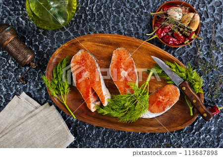 fresh salmon steak raw fish prepared for cooking. Top view on black slate table. fresh salmon steak raw fish prepared for cooking. Top view on black slate table. 113687898