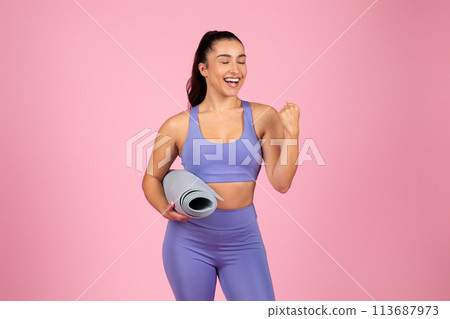 Smiling woman holding a yoga mat joyfully 113687973
