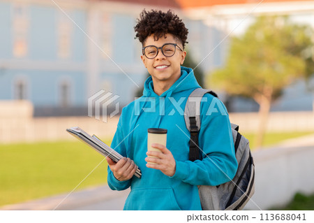 Smiling student holding books and coffee cup Smiling student holding books and coffee cup 113688041