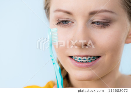 Woman smiling cleaning teeth with braces Woman smiling cleaning teeth with braces 113688072