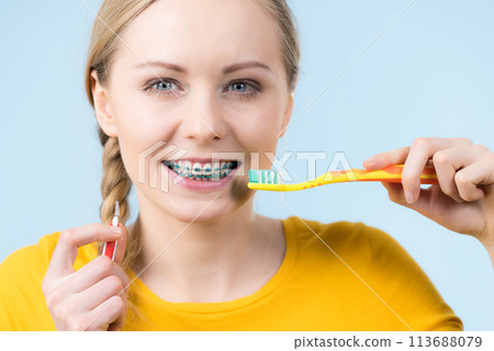 Woman smiling cleaning teeth with braces Woman smiling cleaning teeth with braces 113688079