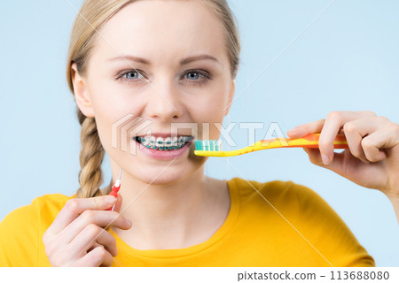 Woman smiling cleaning teeth with braces Woman smiling cleaning teeth with braces 113688080