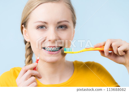 Woman smiling cleaning teeth with braces Woman smiling cleaning teeth with braces 113688082