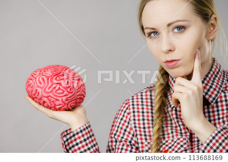 Woman thinking and holding fake brain Woman thinking and holding fake brain 113688169