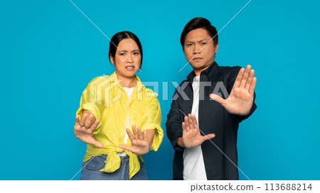 A concerned woman and man extend their hands forward in a stopping motion A concerned woman and man extend their hands forward in a stopping motion 113688214