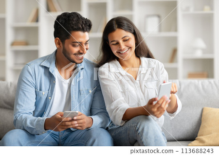 Happy indian couple browsing on phone, relaxed at home 113688243