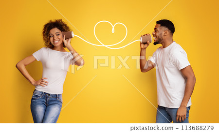 Young black couple with can phone on orange background Young black couple with can phone on orange background 113688279