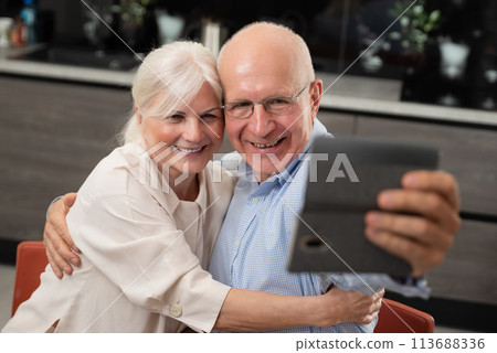 Smiling senior couple taking selfie at home 113688336