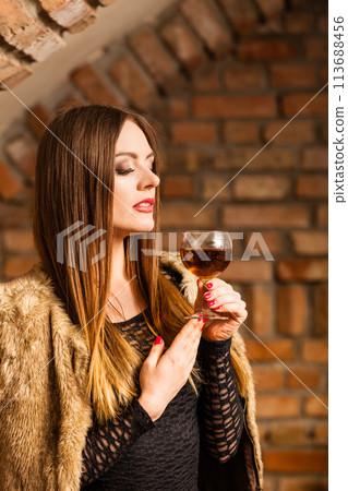 Woman tasting wine in rural cottage interior Woman tasting wine in rural cottage interior 113688456