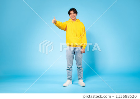Cheerful guy giving thumbs up on blue Cheerful guy giving thumbs up on blue 113688520