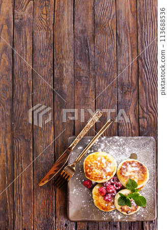 Cottage cheese pancakes with raspberries on wooden background, breakfast or lunch Cottage cheese pancakes with raspberries on wooden background, breakfast or lunch 113688536