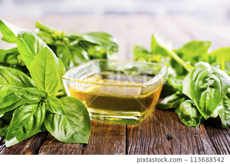 Basil oil and fresh herbs on wooden table Basil oil and fresh herbs on wooden table 113688542