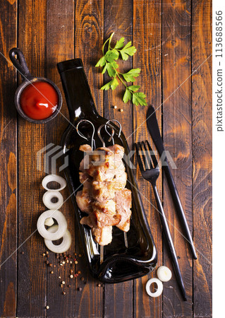 Grilled Lula kebab on skewers with spices in a black plate on a wooden background Grilled Lula kebab on skewers with spices in a black plate on a wooden background 113688566