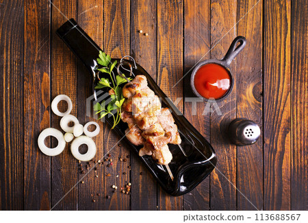 Grilled Lula kebab on skewers with spices in a black plate on a wooden background Grilled Lula kebab on skewers with spices in a black plate on a wooden background 113688567
