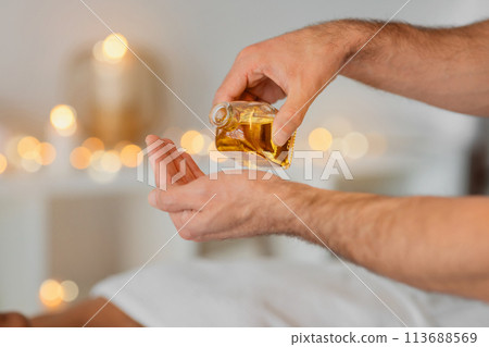 Pouring oil into man masseur hand, closeup Pouring oil into man masseur hand, closeup 113688569