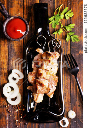 Grilled Lula kebab on skewers with spices in a black plate on a wooden background 113688578
