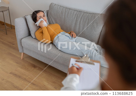 Woman lying on couch in a therapy setting 113688625
