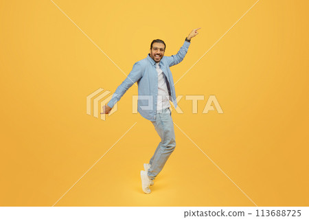 Man dancing joyfully on yellow background Man dancing joyfully on yellow background 113688725