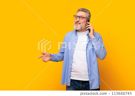 Cheerful senior man talking on cell phone on yellow background 113688745