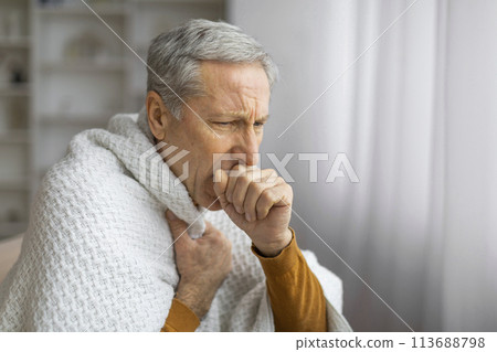 Senior man wrapped in blanket looking unwell Senior man wrapped in blanket looking unwell 113688798