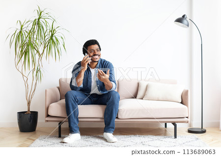Black Man Sitting On Couch And Talking On Cell Phone Black Man Sitting On Couch And Talking On Cell Phone 113689063