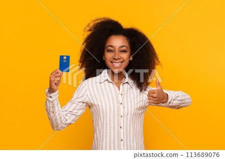 Happy woman holding credit card and thumbs up 113689076