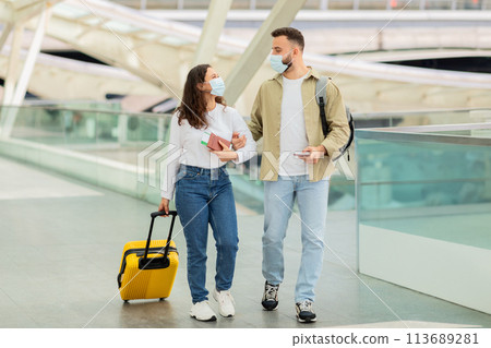 Young Couple In Medical Masks Walking With Suitcase At Airport Hallway 113689281
