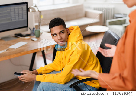 Man holding smartphone in office with another person Man holding smartphone in office with another person 113689344