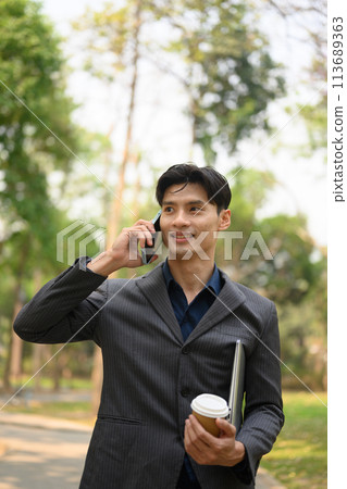 Portrait of handsome businessman having pleased cell phone conversation at outdoor Portrait of handsome businessman having pleased cell phone conversation at outdoor 113689363