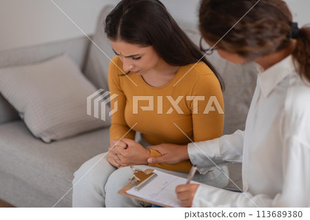 Woman in session with therapist taking notes 113689380