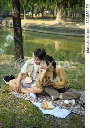 Happy young couple having picnic on a sunny day, spending time together at park 113689459