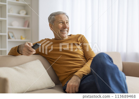Senior man relaxing on sofa with remote control 113689468