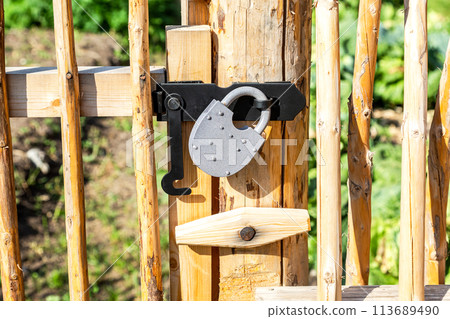 New metal padlock on a bright yellow wooden fence New metal padlock on a bright yellow wooden fence 113689490