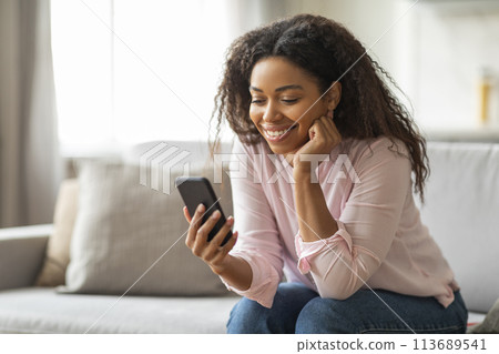 Happy black lady using smartphone at home 113689541