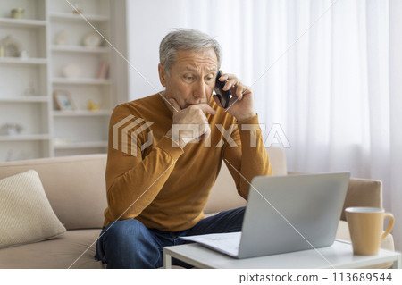 Mature man in conversation holding phone to ear Mature man in conversation holding phone to ear 113689544