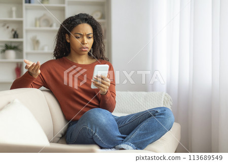 Young Black Woman Experiencing Phone Trouble Indoors During Daytime 113689549