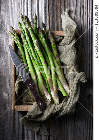 Fresh sprouts of picked asparagus in wooden box 113689684