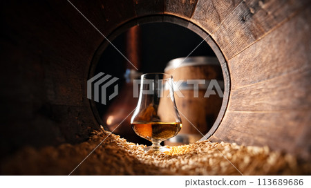 Glass of whiskey in an old wooden oak barrel 113689686