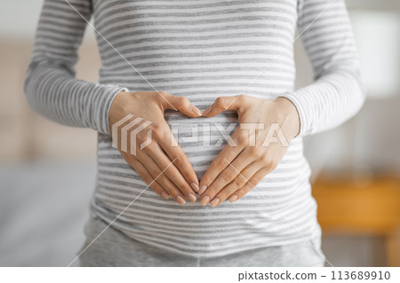 Pregnant woman forming heart shape on belly Pregnant woman forming heart shape on belly 113689910